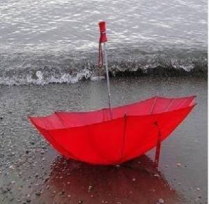 paraigua vermell a la vora del mar