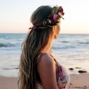 dona noia amb flors al cap platja mar